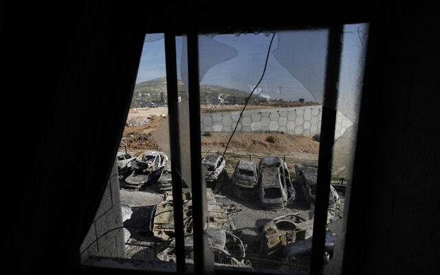  Des voitures brûlées vues à travers une fenêtre brisée dans la ville de Huwara, près de la ville de Naplouse en Cisjordanie, le 27 février 2023. (Crédit : AP Photo/Majdi Mohammed)