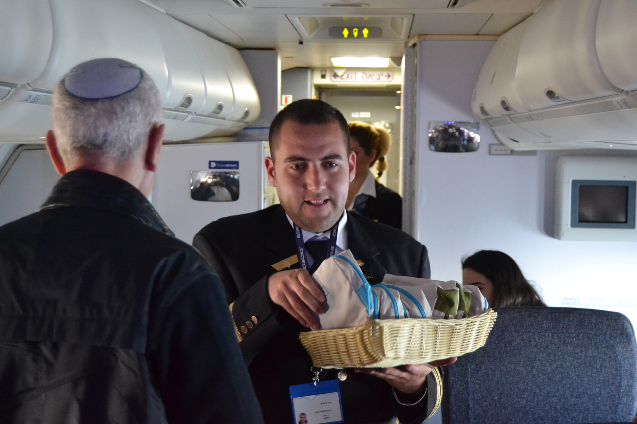  Idan Fishslevich, un jeune homme de 22 ans atteint d'un TSA de haut niveau devenu agent de bord pour une journée, en train de servir les passagers à bord du vol LY383 de Tel Aviv Rome, le 20 février 2023. (Crédit : Tobias Siegal/The Times of Israel)