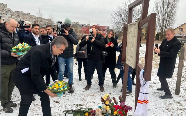 Le ministre des Affaires étrangères, Eli Cohen, déposant une gerbe de fleurs sur la fosse commune de 116 civils tués par les Russes à Boutcha, à Kiev, en Ukraine, le 16 février 2023. (Crédit : Lazar Berman/Times of Israel)