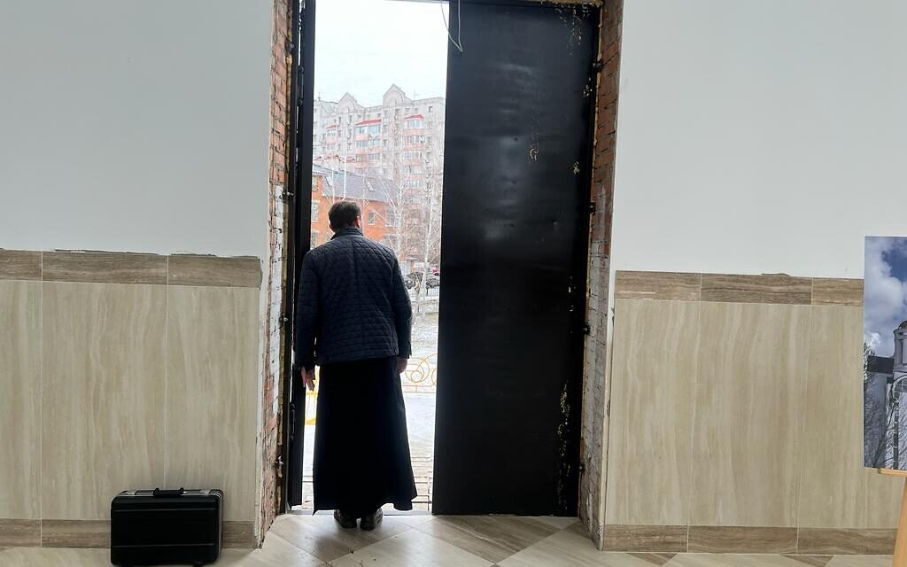 Un prêtre observant la visite du ministre des Affaires étrangères, Eli Cohen, à Boutcha, Ukraine, le 16 février 2023. (Crédit : Lazar Berman/The Times of Israel)