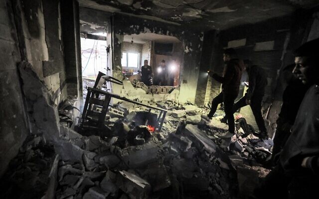 Des personnes inspectant les décombres d'un bâtiment qui abritait un groupe de terroristes palestiniens et qui a été touché par des roquettes lors d'un raid de l'armée israélienne dans le camp de réfugiés palestiniens de Jénine, en Cisjordanie, le 7 mars 2023. (Crédit : Jaafar Ashtiyeh/AFP)