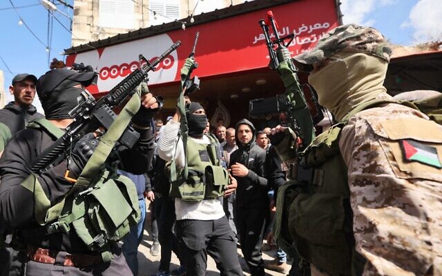 Des terroristes palestiniens brandissant leurs armes lors de la procession funéraire de trois Palestiniens tués par la police des frontières israélienne, à Jaba, en Cisjordanie, le 9 mars 2023. (Crédit :  Jaafar Ashtiyeh/AFP)