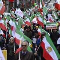 Des manifestants brandissent le drapeau iranien pendant une manifestation en soutien à la résistance iranienne devant le siège de l'Union européenne à Bruxelles, le 20 mars 2023. (Crédit :  John THYS / AFP)