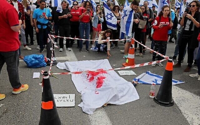 Un manifestant fait mine d'être mort lors d'une manifestation contre la réforme judiciaire à Tel Aviv, le 23 mars 2023. (Crédit : Jack Guez/AFP)