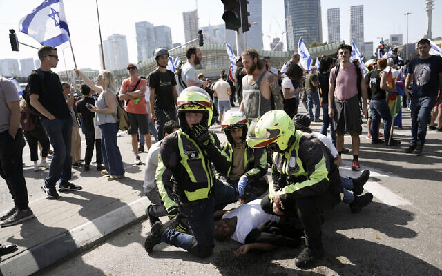 Des secouristes soignent un homme blessé après le déploiement de policiers à cheval et l'utilisation de grenades assourdissantes pour disperser des manifestants qui bloquaient une route principale pour protester contre le projet du gouvernement de réformer le système judiciaire, à Tel Aviv, en Israël, le 1er mars 2023. (Crédit : Oded Balilty/AP)