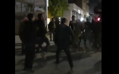 Des habitants des implantations célébrant Pourim dansent avec les troupes de Tsahal dans la ville de Huwara en Cisjordanie, le 6 mars 2023. (Crédit : Capture d'écran/Twitter ; utilisé conformément à la clause 27a de la loi sur le droit d'auteur)