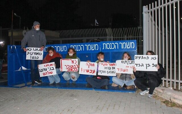Des manifestants contre la réforme judiciaire s'attachent à la porte d'entrée de la Knesset à Jérusalem, le 30 mars 2023. (Crédit : Blocking the Coup)