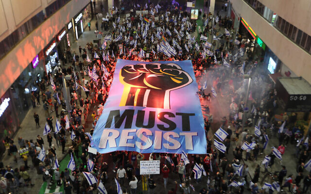 Des Israéliens brandissant une pancarte alors qu'ils manifestent contre les plans très controversés de refonte du système judiciaire du gouvernement, à Tel Aviv, le 4 mars 2023. (Crédit : Jack Guez/AFP)