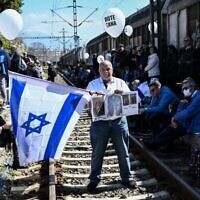 Un participant tient un drapeau israélien à l'ancienne gare de Thessalonique, le 19 mars 2023, après avoir pris part à une marche pour marquer le départ du premier train déportant des Juifs grecs de Thessalonique vers le camp de concentration d'Auschwitz-Birkenau le 15 mars 1943. (Crédit : AFP)