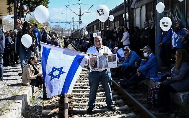 Un participant tient un drapeau israélien à l'ancienne gare de Thessalonique, le 19 mars 2023, après avoir pris part à une marche pour marquer le départ du premier train déportant des Juifs grecs de Thessalonique vers le camp de concentration d'Auschwitz-Birkenau le 15 mars 1943. (Crédit : AFP)