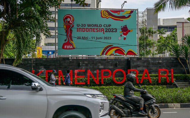 Des automobilistes passent devant une affiche de la Coupe du monde de football des moins de 20 ans Indonésie 2023 à Jakarta le 30 mars 2023. (Crédit : BAY ISMOYO / AFP)