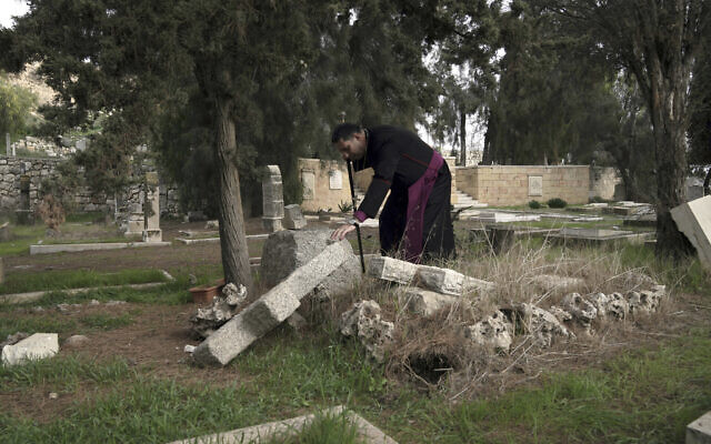 Hosam Naoum, un évêque anglican palestinien, s'arrête là où des vandales ont profané plus de 30 tombes dans un cimetière protestant historique du Mont Sion à Jérusalem, le 4 janvier 2023. (Crédit : Mahmoud Illean/AP)
