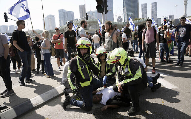  Des secouristes soignant un homme blessé après le déploiement de la police montée et l'utilisation de grenades incapacitantes pour disperser des manifestants qui bloquent une route principale pour protester contre le projet de refonte du système judiciaire du gouvernement, à Tel Aviv, en Israël, le 1er mars 2023. (Crédit : Oded Balilty/AP)