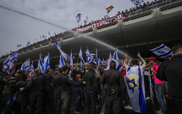 La police israélienne utilisant des canons à eau pour disperser des Israéliens qui manifestent contre la réforme du système judiciaire, à Tel Aviv, le 23 mars 2023. (Crédit : AP Photo/Ohad Zwigenberg)
