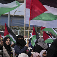 Des femmes palestiniennes agitent des drapeaux lors d’un rassemblement marquant le 47e anniversaire de la Journée de la terre, le long de la barrière frontalière avec Israël, à l’Est de Gaza, le jeudi 30 mars 2023. (Crédit : AP/Adel Hana)
