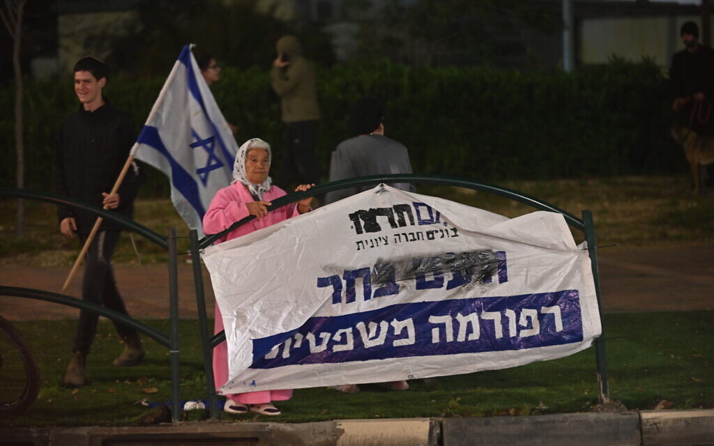 Une femme regarde les manifestants opposés à la refonte judiciaire à Or Akiva, en Israël, le 26 mars 2023. (Crédit : Canaan Lidor)