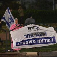 Une femme regarde les manifestants opposés à la refonte judiciaire à Or Akiva, en Israël, le 26 mars 2023. (Crédit : Canaan Lidor)