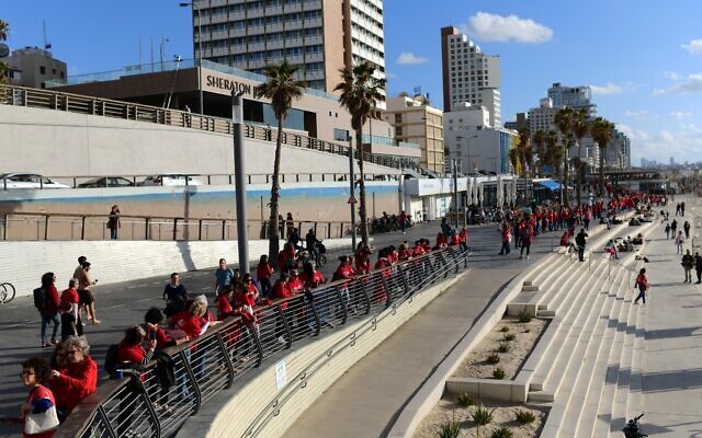 Des centaines de femmes vêtues de rouge marquant la Journée internationale de la femme et manifestant contre la réforme du système judiciaire prévue par le gouvernement, sur la plage de Tel Aviv, le 8 mars 2023. (Crédit : Tomer Neuberg/Flash90)