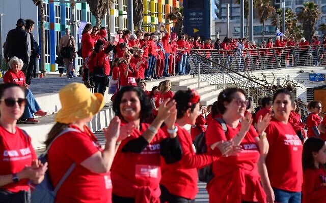 Des centaines de femmes vêtues de rouge marquant la Journée internationale de la femme et manifestant contre la réforme du système judiciaire prévue par le gouvernement, sur la plage de Tel Aviv, le 8 mars 2023. (Crédit : Tomer Neuberg/Flash90)