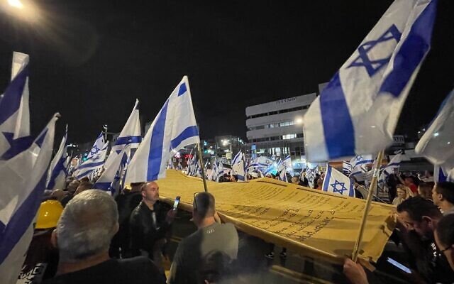Des manifestants anti-gouvernement portant une Déclaration d'Indépendance géante alors qu'ils défilent à Bnei Brak le 23 mars 2023. (Crédit : Carrie Keller-Lynn/Times of Israel)