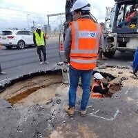 Des travailleurs sur l’autoroute Ayalon de Tel Aviv dépêchés pour examinent et combler le trou qui s'est formé sur la route, le 19 mars 2023. (Crédit : Ayalon Highways Co.)