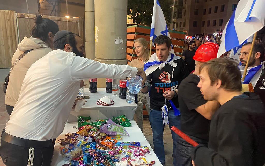 Les résidents offrant des collations et de l'eau aux manifestants venus protester contre la refonte judiciaire, à Bnei Brak, le 23 mars 2023. (Crédit : Haim Uzan)