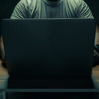 Illustration : Un homme assis avec un ordinateur portable dans une pièce sombre (tanawit sabprasan ; iStock de Getty Images)