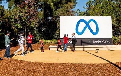 Des personnes visitant le nouveau logo de "Meta", le nouveau nom de la société mère de Facebook, à l'extérieur du siège social de Facebook à Menlo Park, en Californie, le 28 octobre 2021. (Crédit : Noah Berger/AFP)