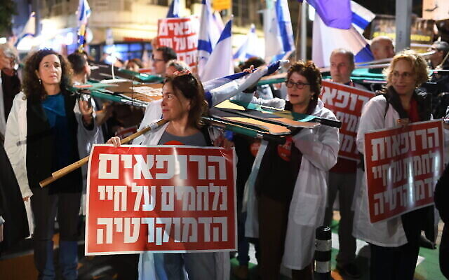 Des médecins israéliens portant le slogan "Doctors Fighting for Democracy" (Médecins luttant pour la démocratie) participant à un rassemblement contre les projets de loi du gouvernement sur la réforme judiciaire, à Tel Aviv, le 25 février 2023. (Crédit : Gili Yaari/Flash90)