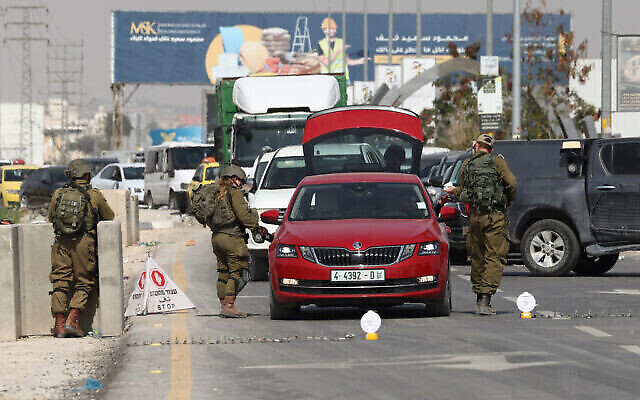 Dossier : Des soldats israéliens fouillant une voiture à un poste de contrôle à l'entrée de la ville de Jéricho, en Cisjordanie, le 28 février 2023. (Crédit : Ahmad Gharabli/AFP)