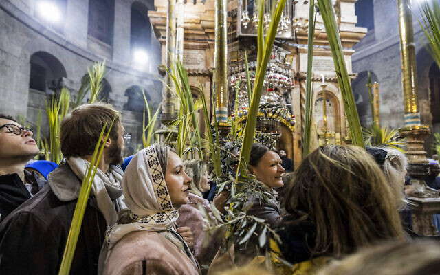 Des pèlerins chrétiens marchant avec des palmes lors d'une procession autour de l'Édicule, traditionnellement considéré comme le lieu de sépulture de Jésus-Christ, lors de la messe catholique du dimanche des Rameaux, à l'église du Saint-Sépulcre à Jérusalem, le 2 avril 2023. (Crédit : Menahem Kahana/AFP)