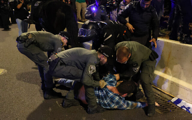 La police israélienne retenant un manifestant lors d'un rassemblement contre les projets de réforme du système  judiciaire du gouvernement, à Tel Aviv, le 15 avril 2023. (Crédit : Jack Guez/AFP)