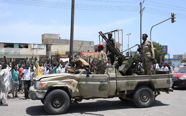 Des Soudanais saluent les soldats de l'armée fidèles au chef de l'armée Abdel Fattah al-Burhan, dans la ville de Port-Soudan sur la mer Rouge, le 16 avril 2023.(Crédit : AFP)
