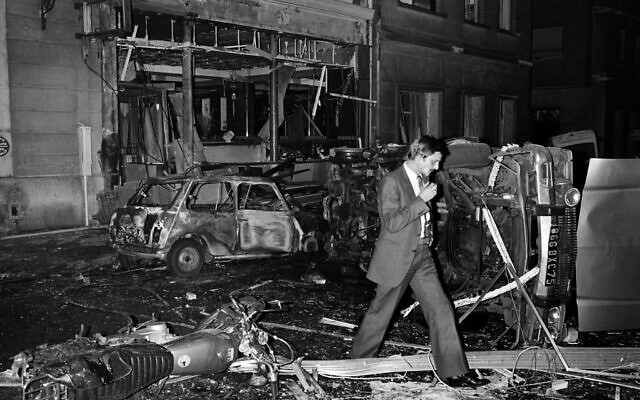 Sur cette photo prise le 3 octobre 1980, un inspecteur marche au milieu des débris de voitures après l'explosion d'une bombe à la synagogue de la rue Copernic à Paris. (Crédit : Georges Gobet/AFP)