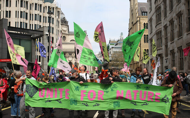 Des manifestants brandissent des pancartes alors qu'ils se rassemblent dans le centre de Londres lors d'une manifestation organisée par le groupe de protestation contre le changement climatique Extinction Rebellion, le 22 avril 2023, à l'occasion de l'événement The Big One organisé par Extinction Rebellion. (Crédit : Susannah Ireland / AFP)
