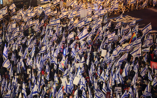 Des manifestants agitant des drapeaux lors d'un rassemblement pour protester contre les projets de réforme du système judiciaire du gouvernement israélien, à Tel Aviv, le 22 avril 2023. (Crédit : Jack Guez/AFP)