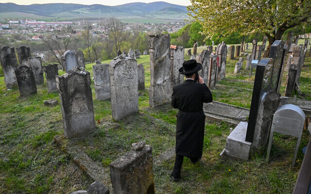 Un pèlerin juif hassidique marche dans le cimetière juif près de la tombe de feu le rabbin miracle Yeshaya Steiner, également connu sous le nom de Rebbe Shayale, dans le village de Bodrogkeresztur, en Hongrie, le 23 avril 2023, lors d'un pèlerinage de juifs hassidiques à l'occasion du 98e anniversaire de la mort du rabbin Steiner. (Crédit : ATTILA KISBENEDEK / AFP)