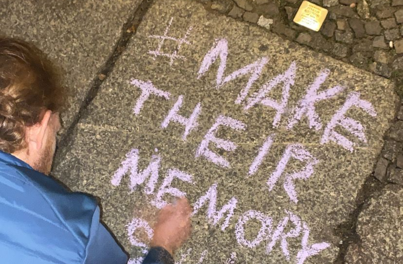 Un bénévole allemand écrit un message à la craie près d'un pavé de la mémoire nettoyé, le 11 novembre 2022. (Autorisation :  MakeTheirMemoryShine)