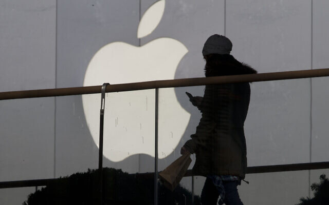 Photo d'illustration : Une femme utilisant un téléphone passe devant le logo d'Apple devant un magasin de Pékin, le 23 décembre 2013. (Crédit : AP Photo/Ng Han Guan, File)