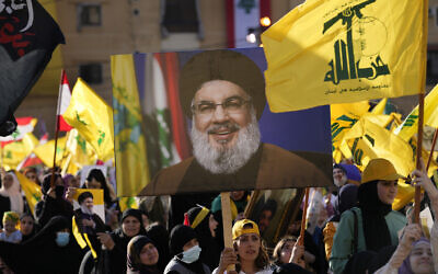 Des partisans du Hezbollah brandissant des portraits du chef du Hezbollah, Sayyed Hassan Nasrallah, et des drapeaux de leur groupe, lors d'une campagne électorale, dans la banlieue sud de Beyrouth, au Liban, le 10 mai 2022. (Crédit  : AP Photo/Hussein Malla)