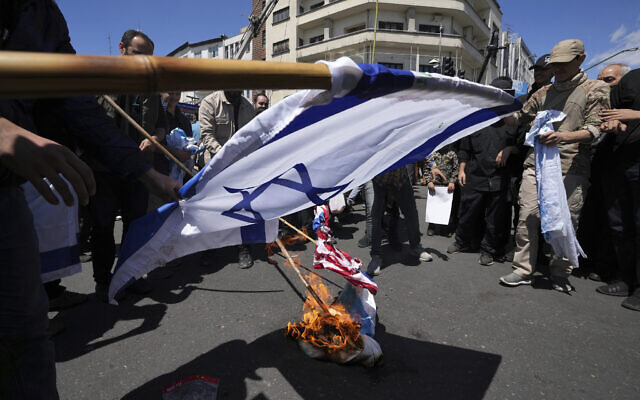 Des manifestants iraniens brûlant des représentations des drapeaux israélien et américain lors de leur rassemblement à l'occasion de la "Journée de Jérusalem", une manifestation annuelle de soutien aux Palestiniens, à Téhéran, en Iran, le 14 avril 2023. (Crédit : AP Photo/Vahid Salemi)