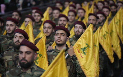 Des combattants du Hezbollah tenant les drapeaux de leur groupe alors qu'ils défilent lors d'un rassemblement pour marquer le Jour de Jérusalem dans la banlieue sud de Beyrouth, au Liban, le 14 avril 2023. (Crédit : Hussein Malla/AP)