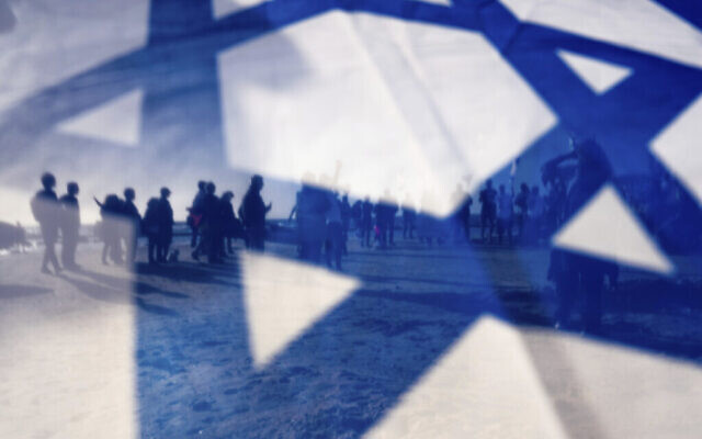 Des manifestants israéliens vus à travers le drapeau national israélien lors d’une manifestation contre le projet de réforme judiciaire du gouvernement du Premier ministre Benjamin Netanyahu, à Césarée, en Israël, le 17 mars 2023. (Crédit : AP Photo/Oded Balilty)