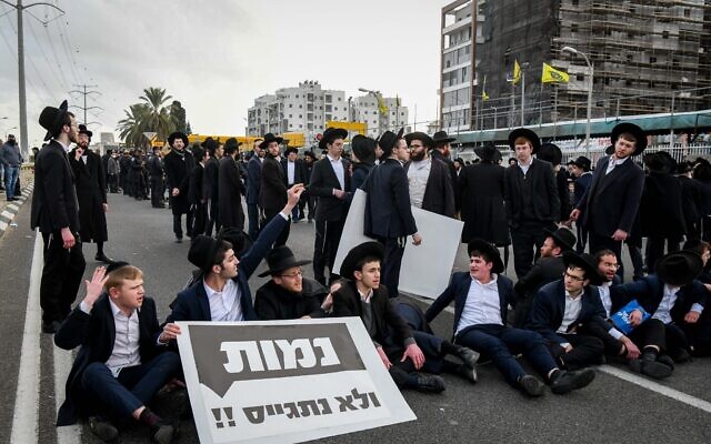 Des Juifs ultra-orthodoxes bloquant une rue pendant une manifestation contre l'obligation du service militaire aux abords de la ville de Bnei Brak, le 9 février 2022. (Crédit : Flash90/Dossier)