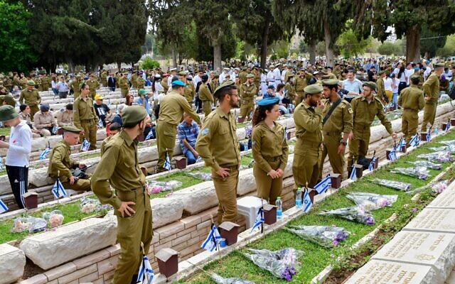 Des civils et des soldats se rendent sur les tombes à l'occasion de la journée commémorative des soldats israéliens tombés au combat et des victimes du terrorisme, au cimetière militaire Nahalat Yitzhak, à Tel Aviv, le 4 mai 2022. (Crédit : Avshalom Sassoni/Flash90)