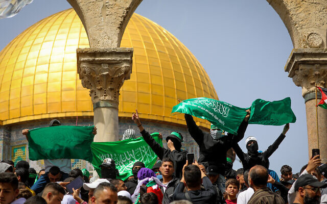 Des Palestiniens brandissant des drapeaux après la prière du vendredi dans l'enceinte de la mosquée Al Aqsa, dans la Vieille Ville de Jérusalem, le 7 avril 2023. (Crédit : Jamal Awad/Flash90)