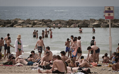 Des Israéliens se pressant sur la plage de Tel Aviv par une chaude journée pendant Pessah, le 9 avril 2023. (Crédit : Avshalom Sassoni/FLASH90)