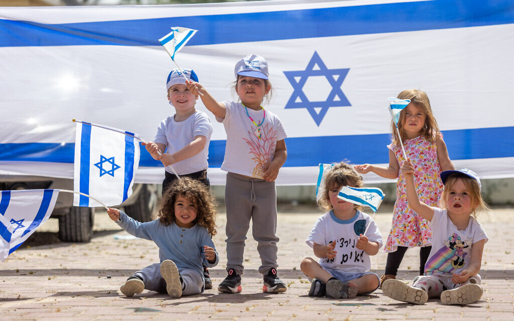 Des enfants jouant avec des drapeaux israéliens à l'approche du 75e anniversaire de l'Indépendance d'Israël, au moshav Yashresh, le 19 avril 2023. (Crédit : Yossi Aloni/Flash90)