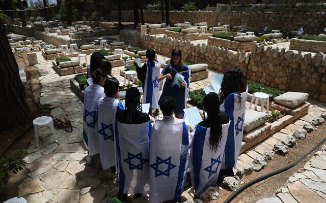 Des personnes portant des drapeaux israéliens visitant le cimetière militaire du mont Herzl à l'occasion de la Yom HaZikaron, à Jérusalem, le 23 avril 2023. (Crédit : Yonatan Sindel/Flash90)