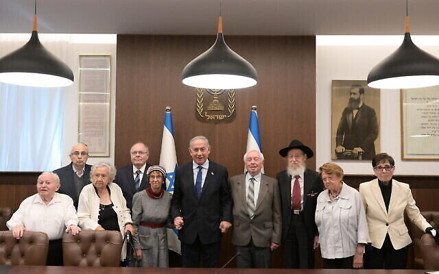 Le Premier ministre Benjamin Netanyahu (au centre) en compagnie de celles et ceux qui vont raviver la flamme du souvenir pour les cérémonies de Son HaShoah, à son bureau de Jérusalem, le 16 avril 2023. (Crédit : Amos Ben Gershom/GPO)